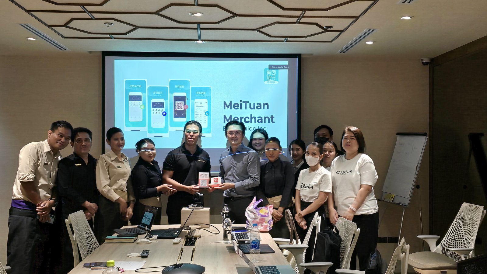 Restaurant team and Klick Digital staff posing together in a meeting room in front of a screen showing a Meituan merchant guideline presentation