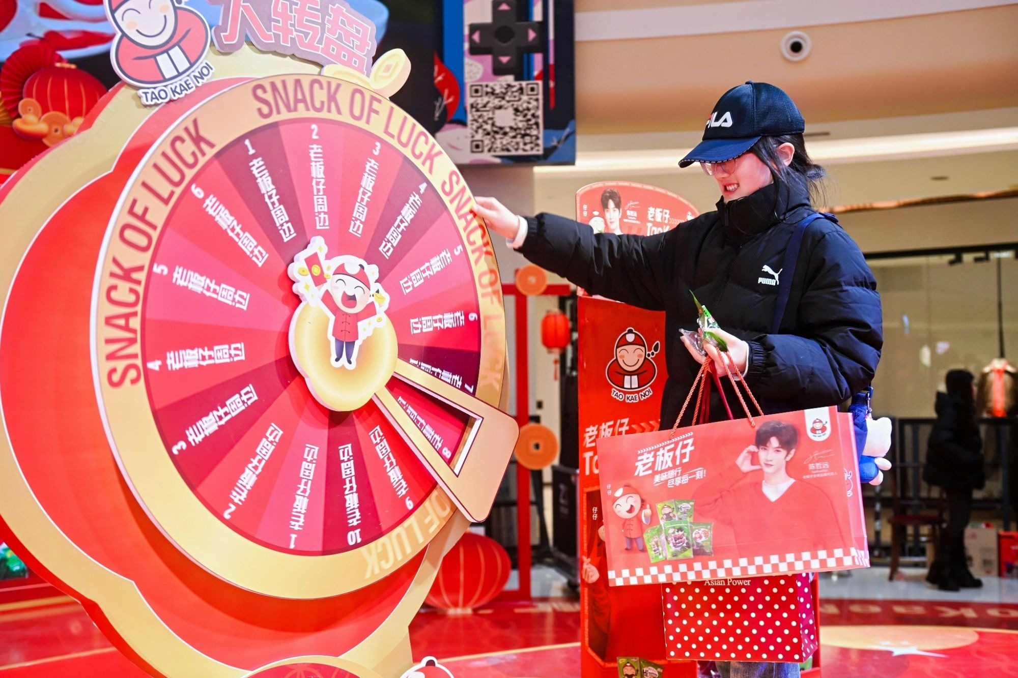 นักช้อปที่มาเข้าร่วมกิจกรรมหมุนวงล้อ Snack of Luck ของ TaoKaeNoi ในอีเวนต์ที่ห้างสรรพสินค้าในฉงชิ่ง